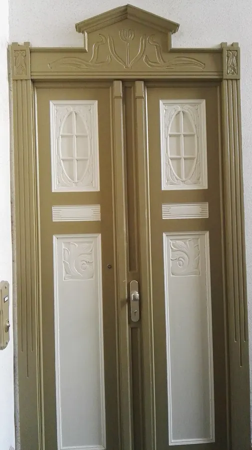 A tall double door with panelled leaves and a carved pediment in a Berlin Altbau apartment