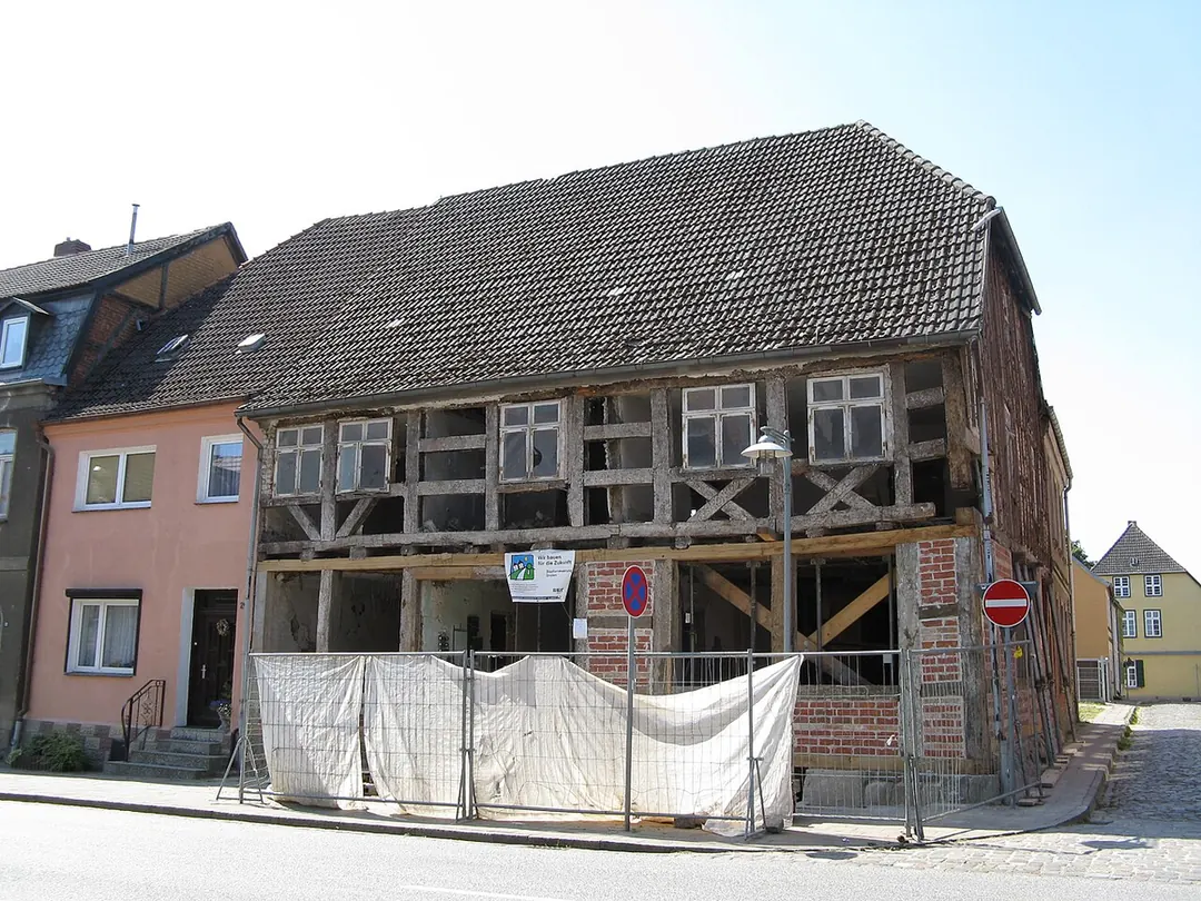 An old half-timbered house in Gnoien in northern Germany, with its frame exposed and screening along the street during renovation