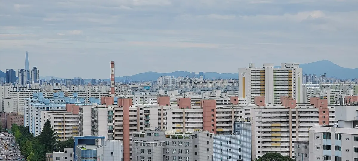 A dense district of high-rise apartment complexes in Seoul with the Lotte World Tower on the skyline