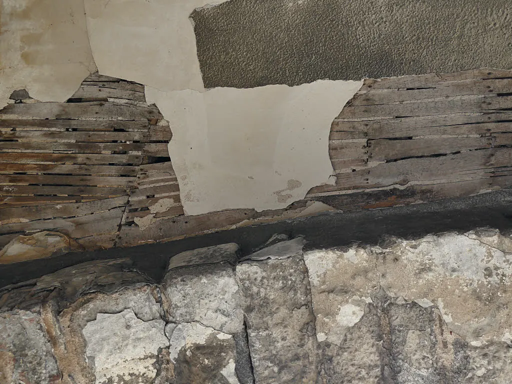 Ceiling plaster broken away to show rows of thin timber laths behind it