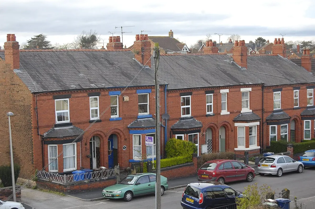 A row of red-brick Victorian terraced houses with bay windows and chimneys