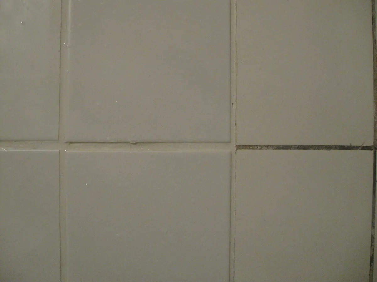 Two tile joints side by side, one filled with light grout and one with dark grout
