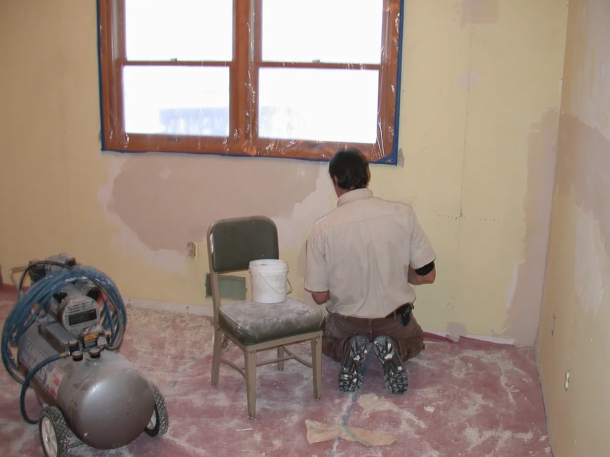 A painted room wall with several patched areas of white compound waiting for primer